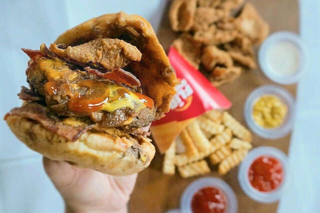 Sebuah tangan sedang memegang burger dari Flip Burger